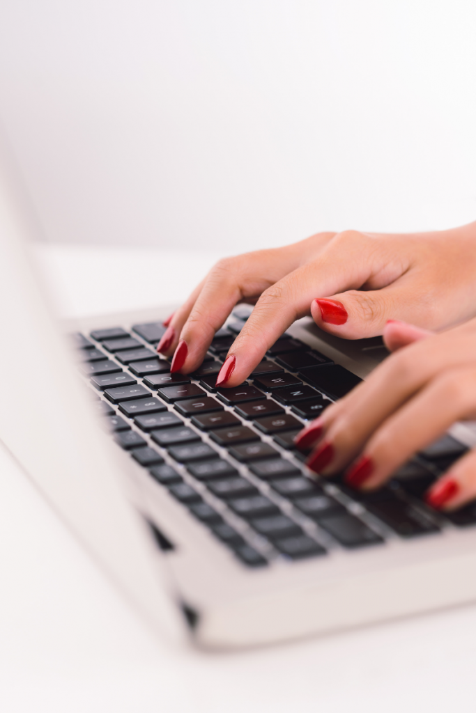 female hands with red nails typing on laptop keyboard